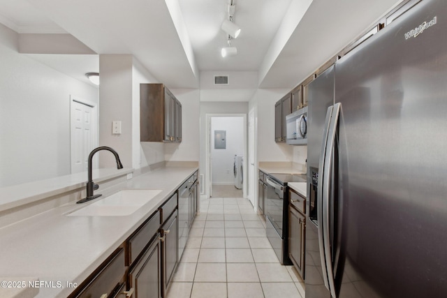 kitchen with appliances with stainless steel finishes, electric panel, sink, rail lighting, and light tile patterned floors