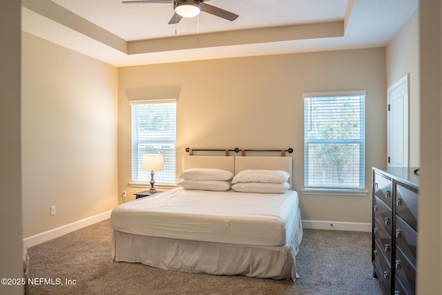 bedroom with ceiling fan, carpet floors, and a tray ceiling