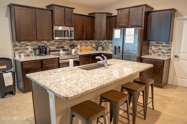 kitchen featuring an island with sink, backsplash, sink, and stainless steel appliances