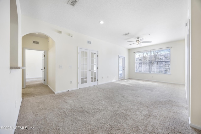 carpeted empty room featuring ceiling fan, french doors, and a textured ceiling