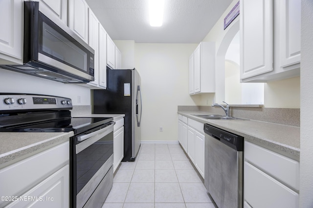 kitchen with sink, white cabinetry, a textured ceiling, stainless steel appliances, and light tile patterned floors