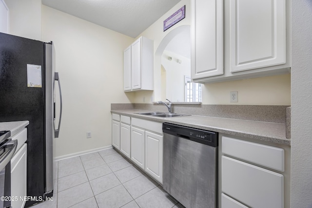 kitchen with light tile patterned floors, sink, white cabinets, and stainless steel appliances