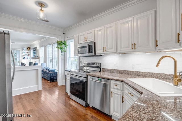 kitchen featuring decorative backsplash, white cabinets, appliances with stainless steel finishes, and sink