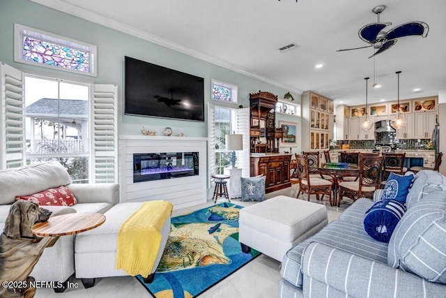 living room with crown molding, plenty of natural light, and ceiling fan