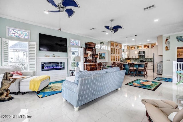 living room with crown molding, plenty of natural light, and ceiling fan