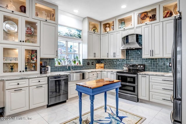 kitchen with tasteful backsplash, wall chimney range hood, stainless steel appliances, and white cabinets