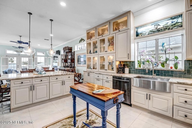 kitchen with pendant lighting, white cabinetry, dishwasher, sink, and light stone countertops