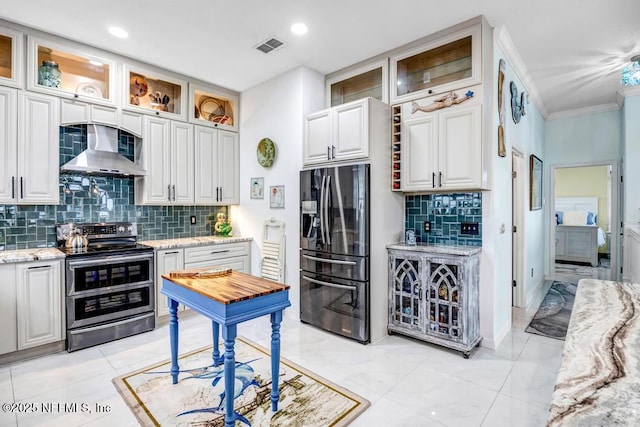 kitchen with light stone counters, white cabinetry, double oven range, refrigerator with ice dispenser, and wall chimney range hood