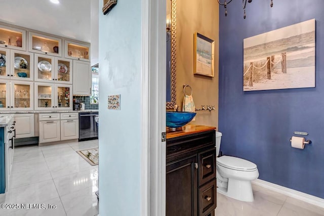 bathroom with toilet, vanity, and decorative backsplash