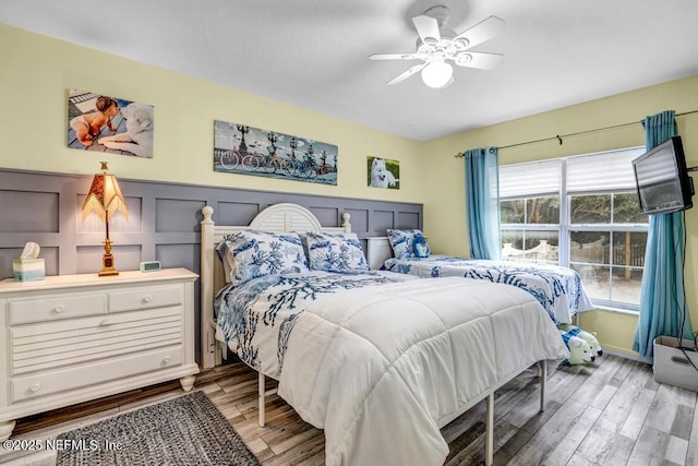 bedroom with multiple windows, wood-type flooring, and ceiling fan