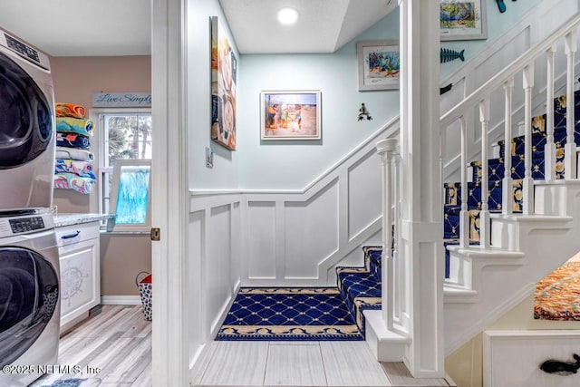 staircase with hardwood / wood-style flooring and stacked washer / dryer