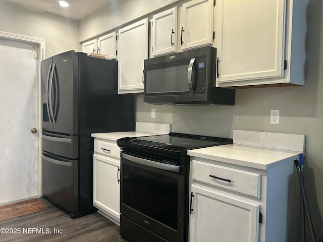 kitchen with dark wood-type flooring, white cabinets, and black appliances