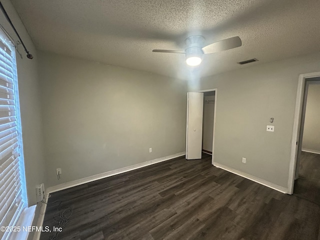 unfurnished bedroom with ceiling fan, a textured ceiling, and dark hardwood / wood-style floors