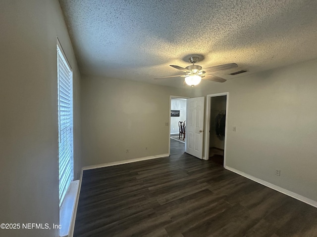 unfurnished room featuring a textured ceiling, dark wood-type flooring, a healthy amount of sunlight, and ceiling fan