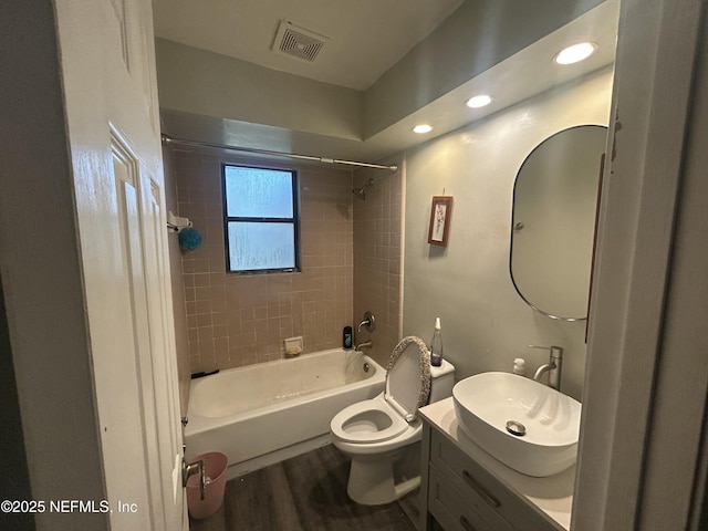 full bathroom with hardwood / wood-style flooring, tiled shower / bath combo, vanity, and toilet