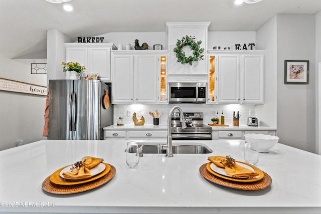 kitchen with stainless steel appliances, white cabinets, tasteful backsplash, and sink