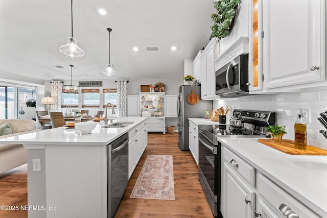 kitchen with sink, light wood-type flooring, a kitchen island with sink, stainless steel appliances, and white cabinets