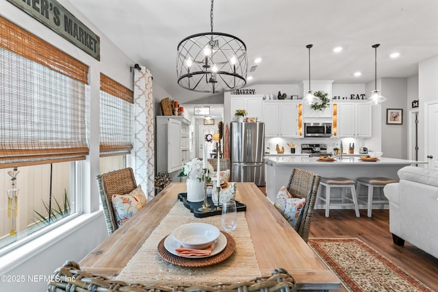 dining area featuring lofted ceiling, dark wood-type flooring, sink, and a chandelier