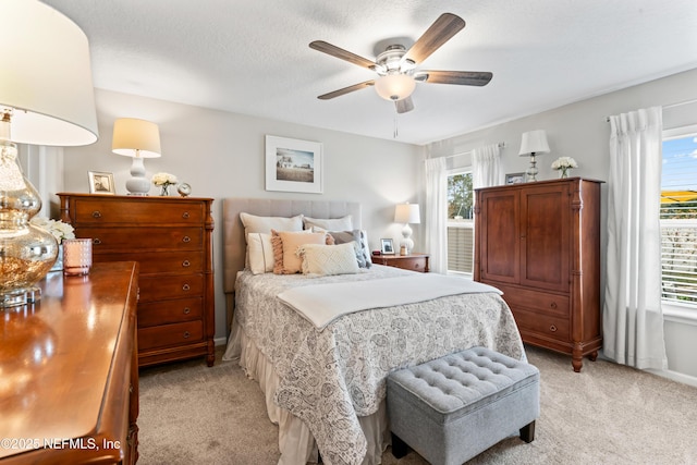 bedroom with light carpet, ceiling fan, a textured ceiling, and multiple windows