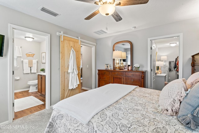 bedroom with ensuite bathroom, ceiling fan, a closet, and hardwood / wood-style flooring