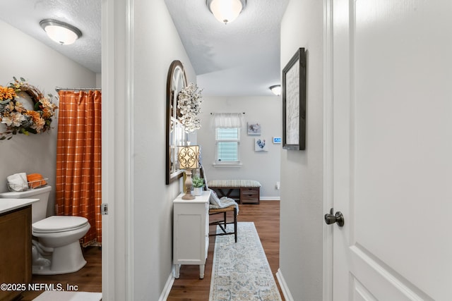 hallway with a textured ceiling and wood-type flooring