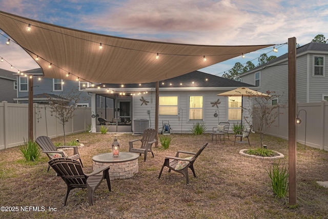 back house at dusk with central AC unit and a fire pit