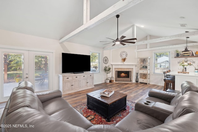 living room with french doors, ceiling fan, hardwood / wood-style floors, and vaulted ceiling with beams