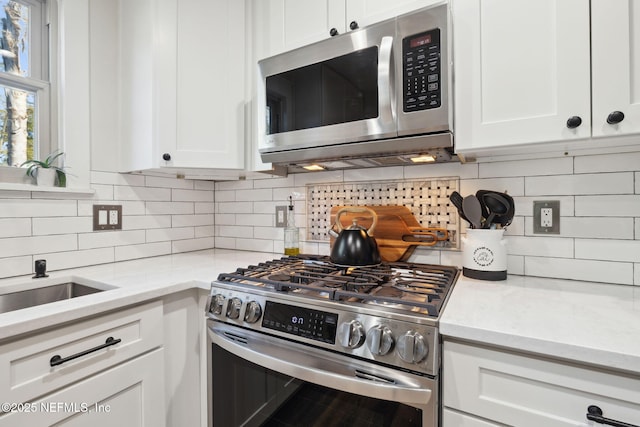 kitchen featuring tasteful backsplash, stainless steel appliances, light stone countertops, and white cabinets