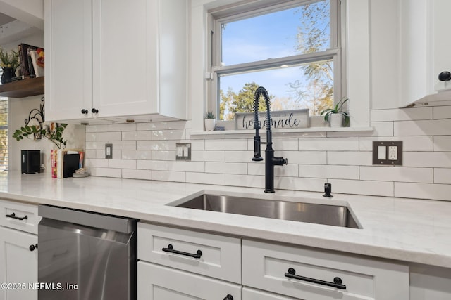 kitchen featuring tasteful backsplash, white cabinetry, sink, and stainless steel dishwasher