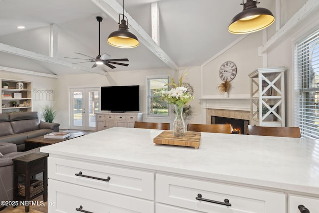 kitchen with pendant lighting, light stone countertops, white cabinets, and lofted ceiling