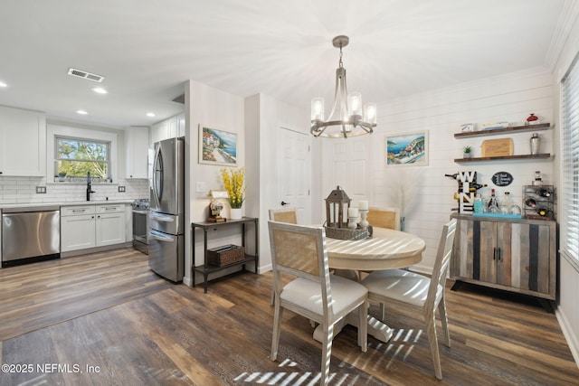 dining room with a notable chandelier, sink, and dark hardwood / wood-style floors