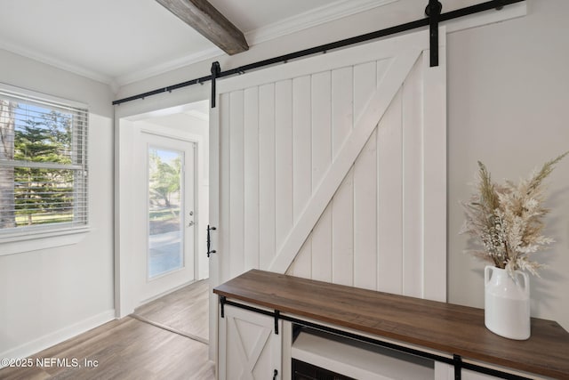 mudroom with crown molding, light hardwood / wood-style flooring, and a barn door