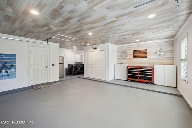 interior space featuring concrete flooring, wooden ceiling, washing machine and clothes dryer, and wooden walls