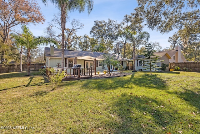 rear view of house with a wooden deck, a yard, and french doors