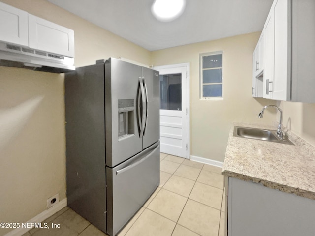 kitchen with light tile patterned floors, sink, white cabinetry, and stainless steel fridge