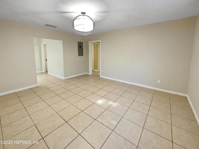 tiled empty room featuring a textured ceiling and electric panel