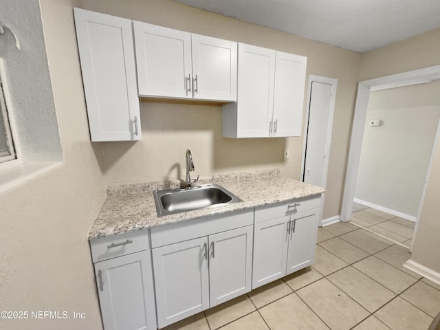 kitchen featuring light tile patterned floors, sink, white cabinets, and light stone countertops