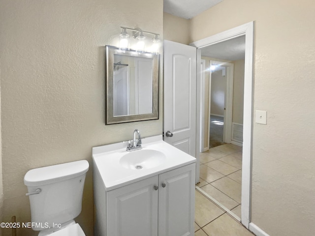 bathroom with toilet, vanity, and tile patterned floors