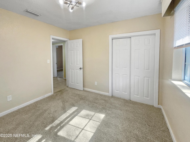 unfurnished bedroom with a closet, carpet flooring, and a chandelier