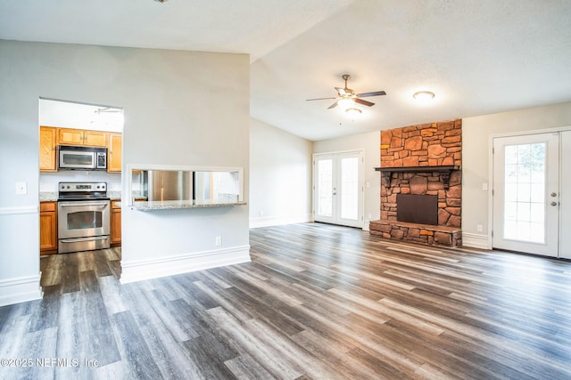 unfurnished living room with dark hardwood / wood-style flooring, a stone fireplace, a wealth of natural light, and french doors