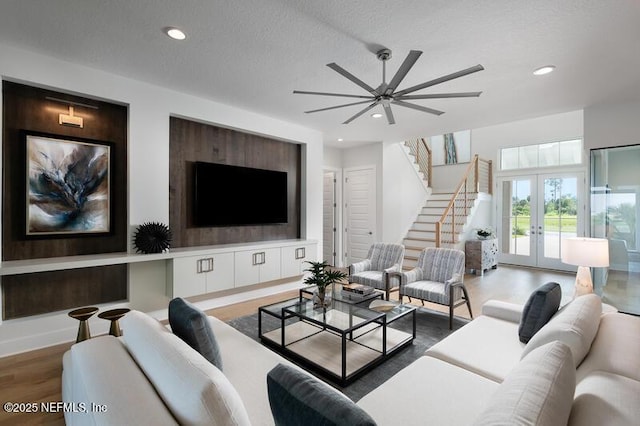 living room featuring ceiling fan, french doors, a textured ceiling, and hardwood / wood-style floors