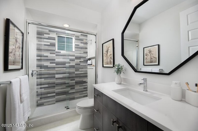 bathroom featuring toilet, vanity, and a shower with shower door