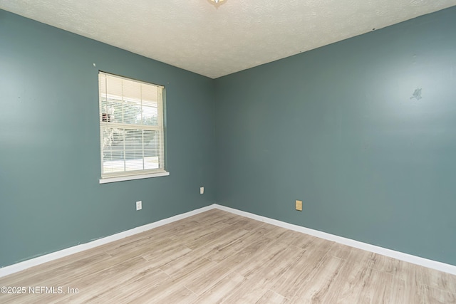 spare room with a textured ceiling and light hardwood / wood-style floors