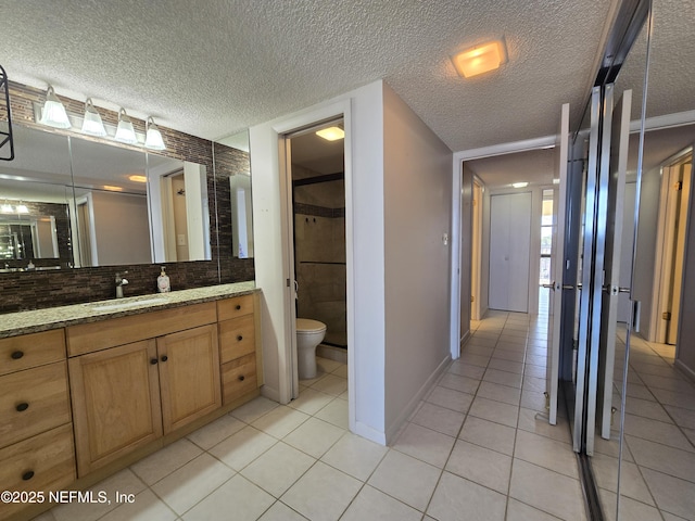 bathroom featuring toilet, tile patterned flooring, and a textured ceiling