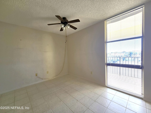 unfurnished room with ceiling fan, a textured ceiling, and light tile patterned floors