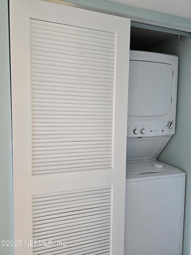 clothes washing area featuring stacked washer and dryer, laundry area, and a textured ceiling