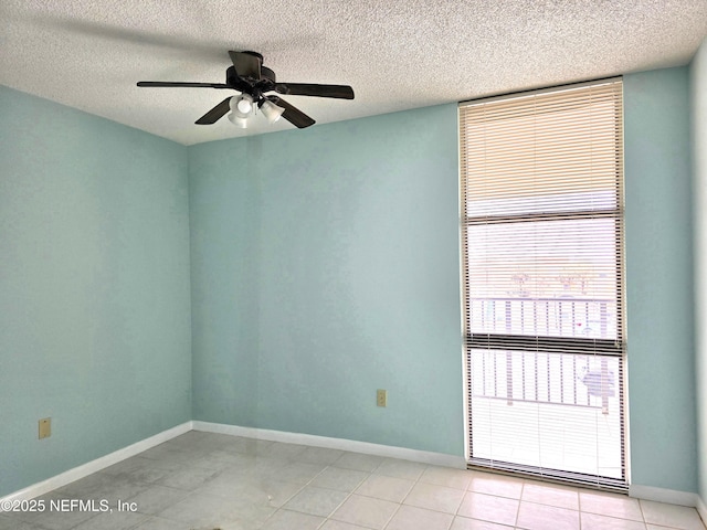 spare room with light tile patterned floors, a textured ceiling, baseboards, and a ceiling fan