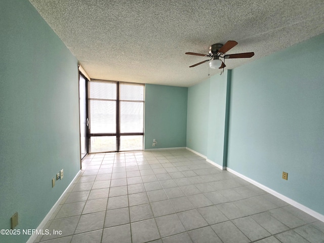 empty room featuring baseboards, a textured ceiling, tile patterned floors, and floor to ceiling windows