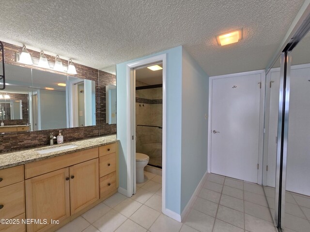 bathroom with a stall shower, vanity, a textured ceiling, and tile patterned floors