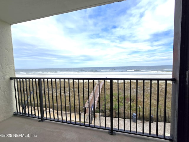 balcony with a water view and a view of the beach